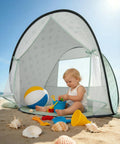 Child playing inside Pop Up Baby Beach Tent With UPF 50+ Sun Shade Mosquito Net Shelter Portable Outdoor Canopy For Babies And Toddlers Green Leaves Pattern Easy Setup Summer Essentials on beach.