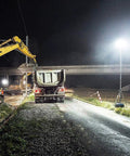 JUDYSSY Spot Lighting Led Floodlight 100W Led Outdoor Flood Lights illuminating a construction site at night with heavy machinery.