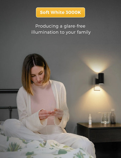 Woman reading in bed with Four Pack Plug In Night Lights With Dimmable Brightness, Light Sensor Auto On Off, Soft White 3000K Black Shade