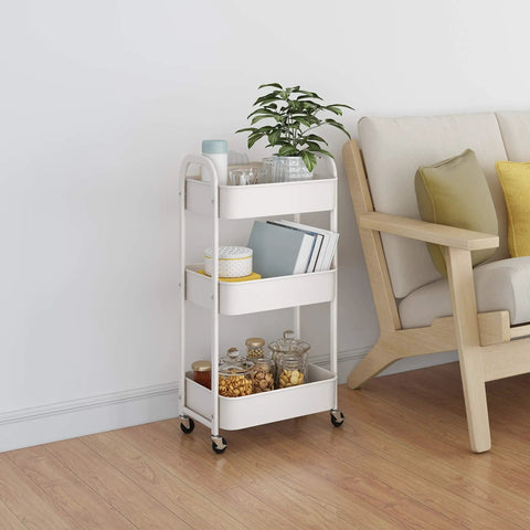 White metal 3-tier rolling utility cart with caster wheels for kitchen and bath, beside a sofa with books and jars, easy glide mobility.