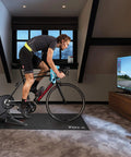 Cyclist using Flux S Smart Bike Trainer Direct Drive With Near Silent Operation, Three Percent Power Accuracy indoors on Zwift app