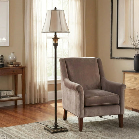 Sophia LED Floor Lamp Tall Mid Century Modern Style with Bell Shape Fabric Shade Bronze Finish next to a gray armchair in a living room.