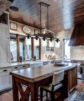 Five Light Farmhouse Dining Room Chandelier Over Table In Matte Black With Rustic Wood Accents And Clear Glass Shades in kitchen
