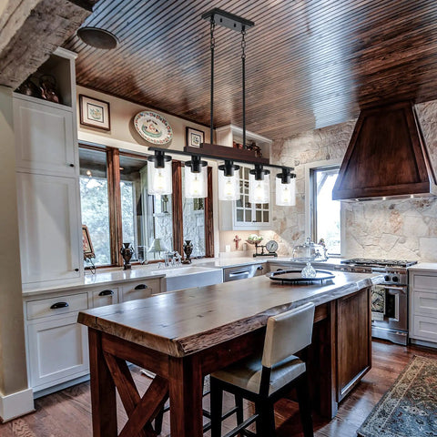 Five Light Farmhouse Dining Room Chandelier Over Table In Matte Black With Rustic Wood Accents And Clear Glass Shades in kitchen