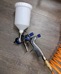 Pro Grade Lvlp Spray Gun Featuring Gravity Feed Reservoir Lightweight Aluminum Body Holds 20 Oz Cup Paired With Exact 1.3 Millimeter Nozzle on wooden surface.