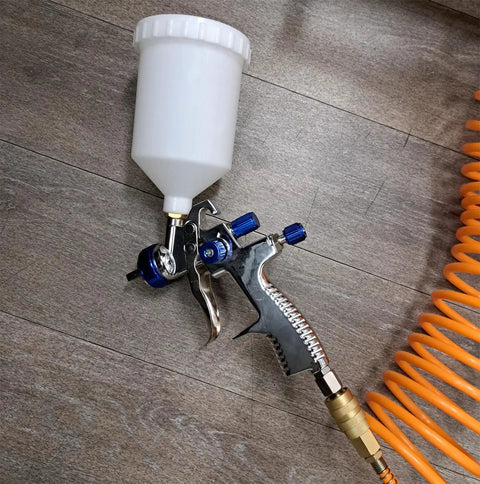 Pro Grade Lvlp Spray Gun Featuring Gravity Feed Reservoir Lightweight Aluminum Body Holds 20 Oz Cup Paired With Exact 1.3 Millimeter Nozzle on wooden surface.