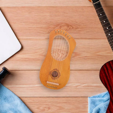 7 String Lyre Harp Starter Kit With Tuning Wrench Extra Strings And Music Sheet Book on wooden background