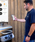 Universal Smart Grill Gauge Thermometer Hub With Wi Fi And Bluetooth For Kamado Joe Weber Grills And Smokers Replacement Accessory 3.5 Inch Length 0.3 Inch Diameter Not For Big Green Egg For Grill Lovers Who Want Pro Level Monitoring On The Fly next to a man using smartphone app with grill in background