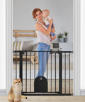Wide Auto Close Baby Gate With Cat Door For Easy Walk Through Adjustable 29.7 To 40.6 Inches Pressure Mounted Or Hardware Mounted Durable Pet Gate For Stairs And Doorways Black, showing woman holding baby and cat by gate