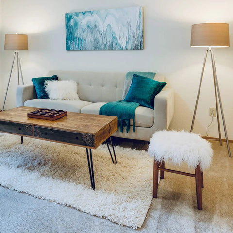 Modern living room with sofa, wooden coffee table, two floor lamps with Efficient A19 LED Light Bulbs 60W Equivalent Soft White 2700K Non Dimmable 9W Energy Saver With E26 Standard Base 10,000 Hour Lifespan Ideal For Home Lighting 24 Pack providing soft lighting, and abstract wall art.