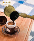 Old School Hand Hammered Solid Brass Copper Ibrik Pot Coffee Maker With Wooden Handle pouring coffee into a cup