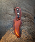 Generational USA Fixed Blade Knife With Three Point Five Inch Clip Point Skinner in leather sheath on textured surface