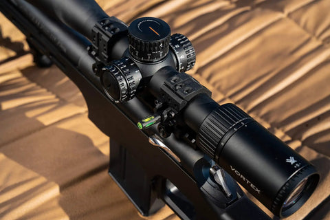 Close-up of two piece Picatinny scope rings with anti cant indicator on a rifle, showcasing flat top rings and lock nuts.