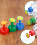 Three Pack Bottle Cap Sprinkler Nozzles for DIY irrigation in red, green, blue on wood surface with plastic bottles attached