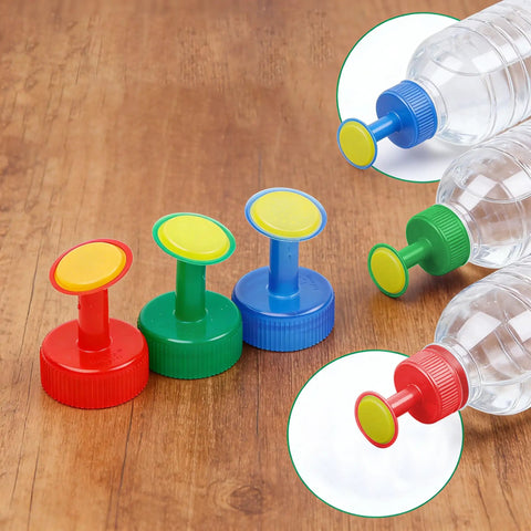 Three Pack Bottle Cap Sprinkler Nozzles for DIY irrigation in red, green, blue on wood surface with plastic bottles attached