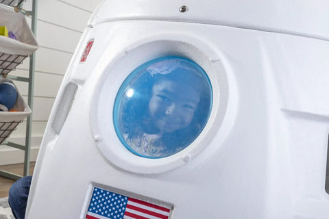 Child peering through window of Space Capsule Swing For Kids Indoor Outdoor Playhouse Two In One Backyard Playground Set
