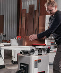 User operates a six inch long bed jointer featuring helical cutterhead and 27 carbide inserts in a workshop.