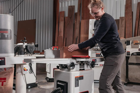 User operates a six inch long bed jointer featuring helical cutterhead and 27 carbide inserts in a workshop.