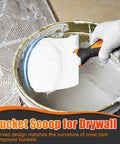 Person using bucket scoop for drywall to mix joint compound in a bucket, with glove and detailed tile background.