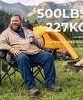 Man sitting on Oversized Folding Camping Chair With 500 Lbs Support, Padded Cushion And Built-In Cooler Pockets, in camping setting