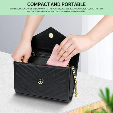 Front view of black quilted crossbody purse with gold chain; pink microfiber cleaning cloth being placed inside.