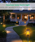 Lit Solar Flame Torch Lights For Outdoors With 99 LED Flickering Flames 43 Inch Waterproof Pathway Lights Solar Powered Backyard Garden Patio Lighting Four Pack illuminating a pathway at night.
