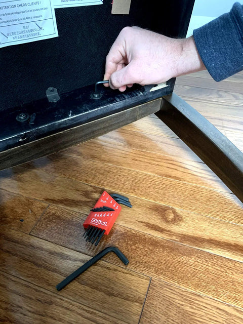 Hand using SAE Hex Key Set In Inch Sizes From.050 To 1/4, 11 Pc Short Series Allen Wrenches for furniture assembly, red holder on floor