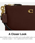 Close-up of Top Shelf Small Wristlet Crafted From Smooth Pebble Leather With Signature Hardware showcasing the glossy finish.