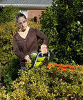 Person using 24-Inch 40-Volt Lithium-Ion Cordless Hedge Trimmer Bare Tool with dual-action blades on hedges outdoors