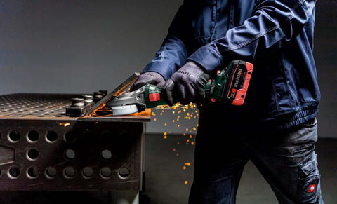 User operating Built Tough Brushless 18V Cordless Flat Head Angle Grinder 125 MM Disc on metal with sparks flying.