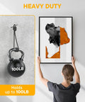 Woman hanging artwork using 40 Pack Picture Hangers Super Hooks For Drywall No Tools Needed Holds Up To 100 Lbs Silver Finish Heavy Duty Design.