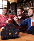 Novabright Vintage Copper Steampunk Gear Train Figurine on a desk with people in the background holding beer mugs.