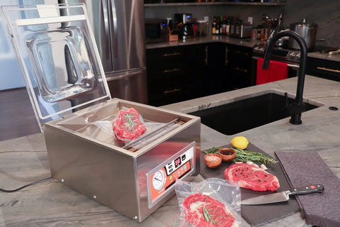 Chamber Vacuum Sealer CM255 For Home And Commercial Kitchens, in a kitchen setting with open lid and steak inside, on a countertop.