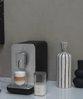 No Sweat Brewing Fully Automatic Espresso Machine With Integrated Grinder And One Touch Milk Frother For Silky Lattes Bold Shots And Ten One Tap Presets 19 Bar Pressure Compact Space Saving Matte Black on a marble surface.