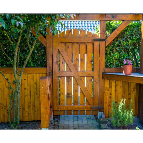 Wooden garden gate with black gate hinges with screws, installed, surrounded by lush greenery, showcasing durable outdoor use.
