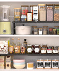 Hella Adjustable And Stackable Kitchen Cabinet Organizer displaying jars and spices on a metal pantry shelf in a kitchen cupboard.