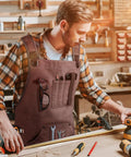 Mens Heavy Duty Canvas Shop Apron With Nine Deep Tool Pockets Water And Oil Resistant Pro Workhorse Gear Built Like A Tank For Woodworking And All Day Shop Tasks worn by a man in a woodworking shop.