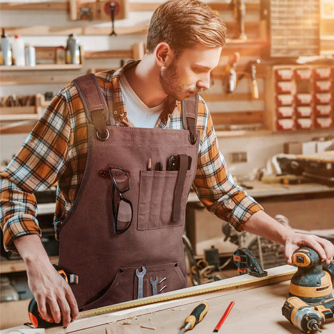 Mens Heavy Duty Canvas Shop Apron With Nine Deep Tool Pockets Water And Oil Resistant Pro Workhorse Gear Built Like A Tank For Woodworking And All Day Shop Tasks worn by a man in a woodworking shop.