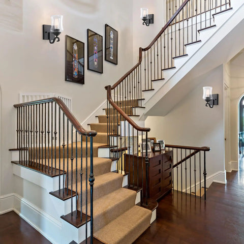 Winsmart Black Wall Sconces Set of Two Hard Wired, mounted on staircase wall, illuminating clear glass shade for ambiance.
