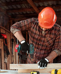 Person using a drill on wood in workshop, wearing safety gear and working on project, tools visible in background.