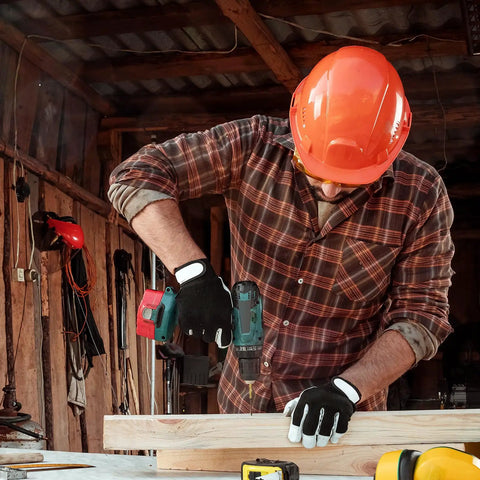 Person using a drill on wood in workshop, wearing safety gear and working on project, tools visible in background.