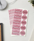 Hot Pink Fragile Stickers For Shipping Do Not Bend Do Not Crush Handle With Care Labels Pack Of 500 on a desk