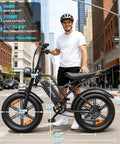 Person standing next to Fat Tire Electric Mountain Bike All Terrain E Bike With 1500W Peak Motor in an urban street setting.