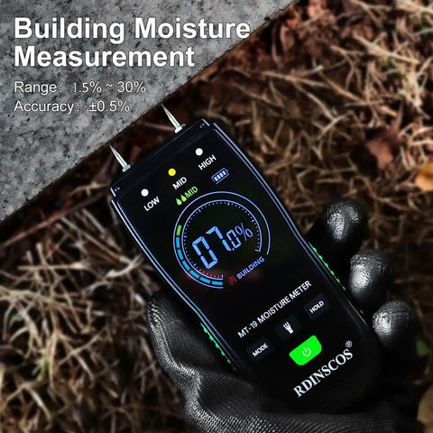 Gloved hand holding a digital wood moisture meter with pin probes for firewood, drywall, and lumber. Screen displays building moisture level.