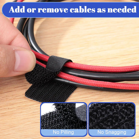 Close-up of a black self-adhesive hook-and-loop cable tie managing red and black cables on a desk surface