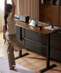 Top Shelf Electric Standing Desk With Ultra Wide Worktop Effortless Height Adjustment Hidden Wire Basket Natural Walnut Finish in home office.