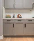 Kitchen with matte black stainless steel cabinet pulls installed on gray cabinetry, focus on Thirty Pack Matte Black Stainless Steel Cabinet Pulls.