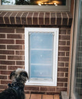 Premium Wall Mount Pet Door In White Xl Featuring Energy Efficient Double Flap Design with a dog looking at the door.