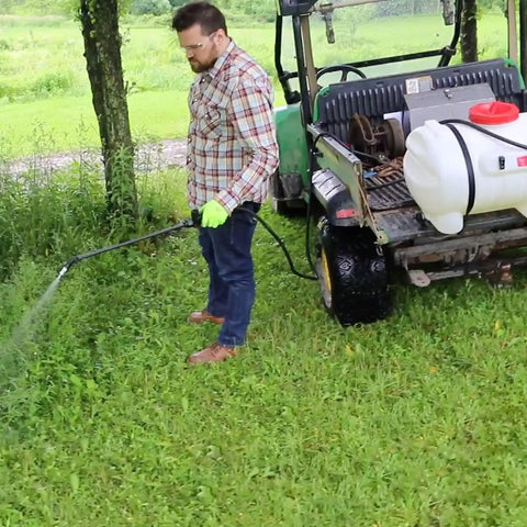 15 Gallon ATV UTV Spot Sprayer With 18 Inch Spray Wand, 12 Volt Diaphragm Pump, Filtration System, EZ Mount Quick Connect, No Shaft Or Seal Replacements, Translucent White Poly Tank For Lawn Care And Chemical Mixing. Man spraying grass from ATV-mounted translucent white poly tank