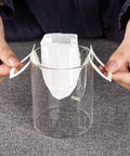 Hands setting up Go To Portable Coffee Filter Bags With Hanging Ear Design on a glass cup for single serve coffee.